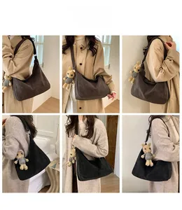 Detail view of large retro suede hobo tote bag in black and dark brown with bear charm