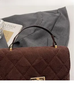 Detail of dark brown quilted velvet bucket bag with gold hardware and chain strap