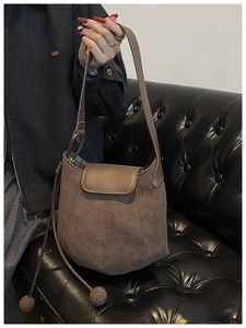 Detail view of brown matte suede bucket bag with decorative drawstrings and magnetic flap