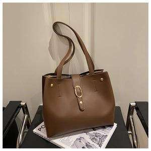 Vue détaillée de la boucle dorée et du cuir grainé sur le sac fourre-tout marron