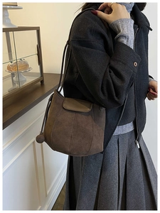 Detail of dark brown suede bucket bag with stitched panels and decorative bead accent