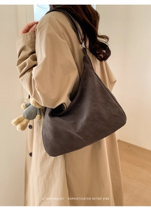 Close-up of minimalist dark brown matte suede hobo bag styled with a beige trench coat