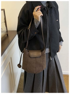 Detailed macro of coffee brown suede bucket bag with round charm and matte finish