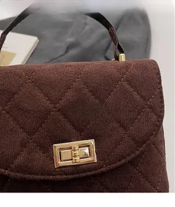Detail of brown quilted velvet handbag featuring gold metallic twist lock closure