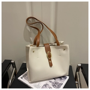 Vue détaillée d'un sac cabas crème avec sangles marron, boucles d'or et rivets fins