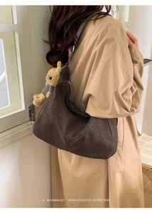Close-up of brown hobo bag with cute plush rabbit charm on a minimalist shoulder strap