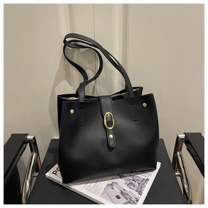 Gros plan du sac cabas noir mat avec boucle dorée et rivets sur un magazine