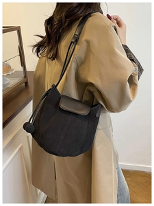 Detail of black suede bucket bag featuring petal-shaped patchwork and ball drawstring charm