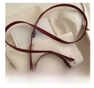 Close-up of glossy burgundy patent leather shoulder strap with gold hardware on blazer