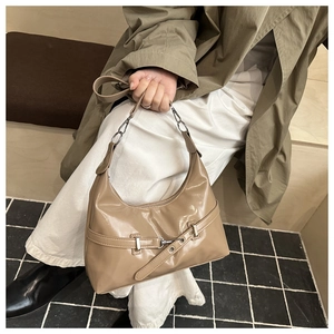 Close-up of a glossy khaki underarm bag with metal buckle and chain strap detail