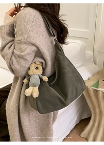 Close-up of minimalist retro shoulder bag with plush bunny charm on a model