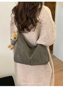 Detail of dark olive hobo bag with teddy bear pendant on a model in vintage style