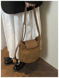 Detail of brown suede bucket bag with smooth leather strap and drawstrings