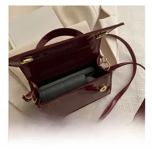 Interior view of vintage burgundy patent leather crossbody bag showing phone and wallet