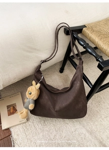 Detail of coffee brown suede hobo bag with adjustable strap and cute rabbit pendant