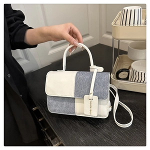 Detail der Handtasche mit weißem Leder und grauer Stoffstruktur im Farbblock-Design