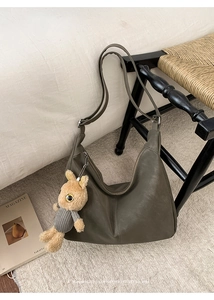 Detail of olive green retro hobo bag with soft matte texture and cute plush rabbit charm