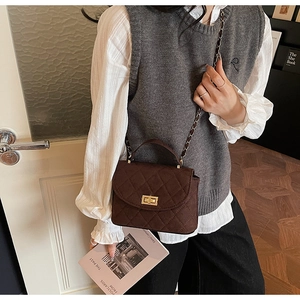 Brown quilted crossbody bag with gold hardware and chain strap on stylish model