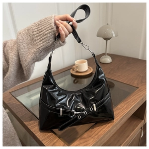 Detail of glossy black underarm bag with decorative belt buckle and metal eyelets