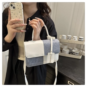 Details der Kontrast-Handtasche mit strukturiertem grauen Stoff und weißem Lederriemen