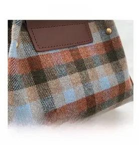 Macro detail of textured plaid fabric hand bag with leather patch and gold studs
