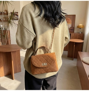 Detail view of brown quilted suede crossbody bag with metallic turn-lock and chain strap