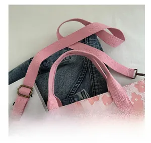 Detail of pink floral jacquard tote bag featuring cotton webbing handles and bronze buckle