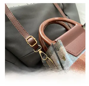 Detail of adjustable gold buckle, vintage plaid fabric, and glossy resin handle