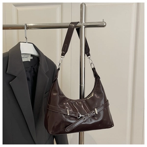 Detail of dark brown glossy patent leather shoulder bag with silver buckle and eyelets