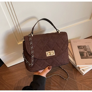 Macro detail of brown quilted leather bag with gold twist lock and chain strap