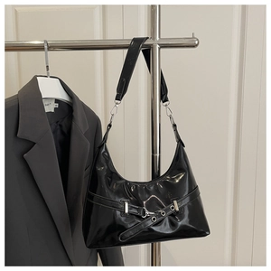 Detail of black patent leather underarm bag with silver hardware and grommet belt