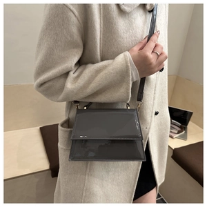 Gray patent leather crossbody bag with thin strap shown on model in modern setting