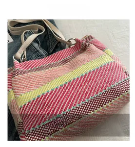 Détail du sac tissé à rayures multicolores avec boucles en métal et anse blanche