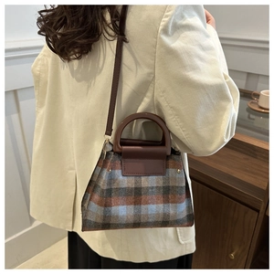 Side view of a vintage plaid crossbody bag with brown leather strap on a model outfit