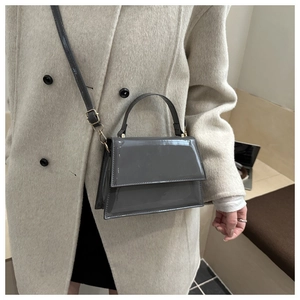 Detail showing grey patent leather texture and gold hardware on the crossbody bag