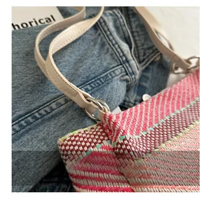 Détail du sac tissé rose et violet avec bandoulière en cuir blanc et boucle argent