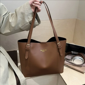 Brown leather tote bag with gold lettering shown in a stylish lifestyle office setting