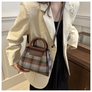 Detail of vintage plaid wool tote bag with leather strap on a model beige blazer
