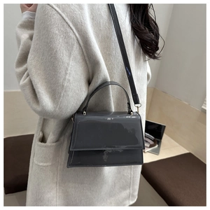 Side view of a vintage grey patent leather crossbody bag worn by a model in casual setting