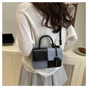 Detailansicht einer farbblockierten quadratischen Tasche mit Schachbrettmuster und Anhänger