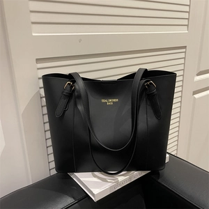 Minimalist black large capacity tote bag with gold lettering on elegant white stand