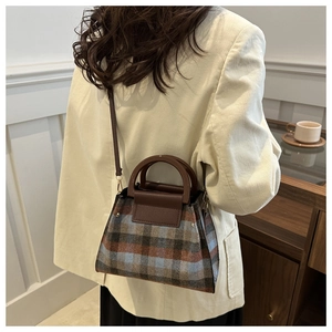 Detailed close-up of a vintage plaid tote bag with brown leather handles and hardware