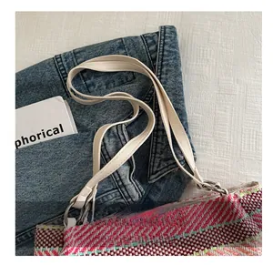 Détail d'un sac à main tissé multicolore avec fines anses en cuir blanc et anneaux