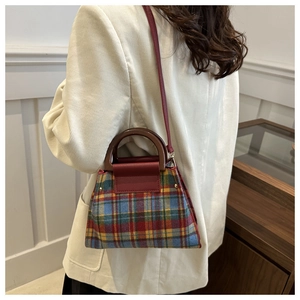 Close-up of vintage plaid handbag with wooden handles on a light corduroy blazer