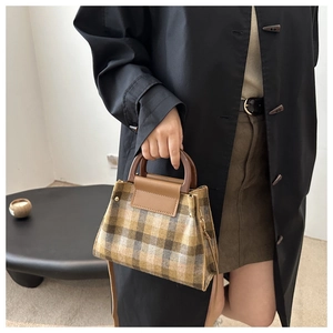 Detailed view of plaid tweed handbag with brown resin handle and leather flap texture