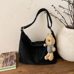 Black matte crescent shoulder bag with cute plush bunny charm on a wooden surface