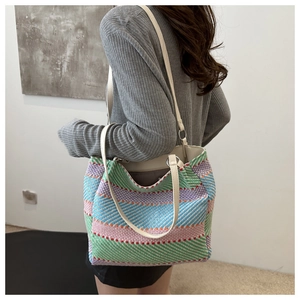 Détail du sac cabas tissé à rayures colorées avec bandoulière blanche et anneau métallique