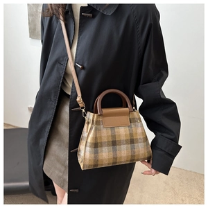 Close-up of vintage plaid handbag with brown leather handle and gold hardware detail