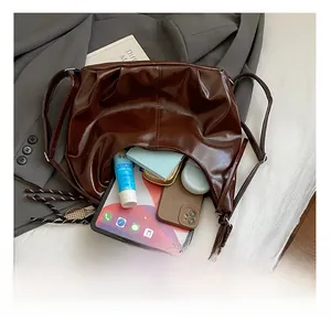 Détail d'un sac porté épaule marron foncé brillant avec effet cuir plissé vintage