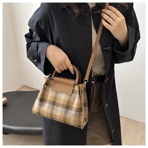 Plaid tote bag with wooden handles styled with a dark trench coat on a model